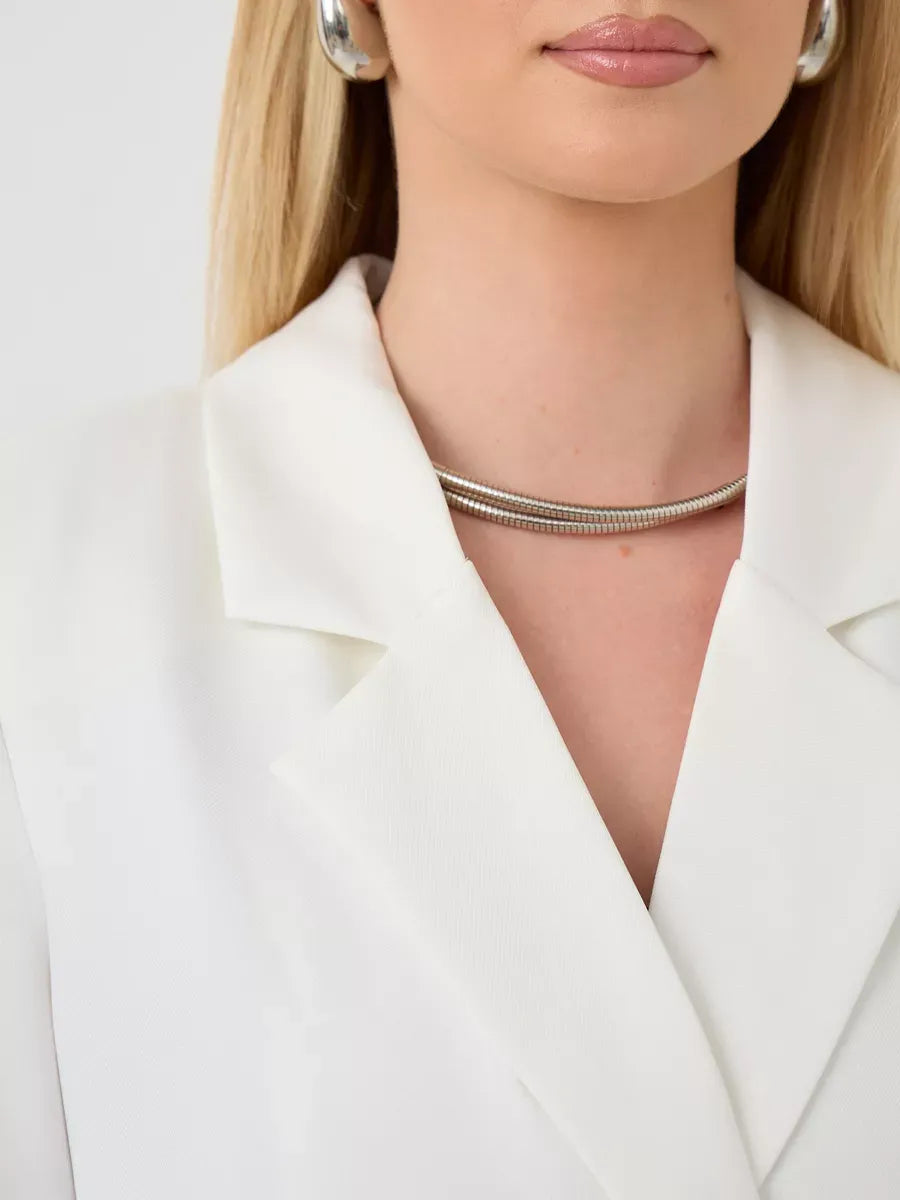 Close-up of a woman wearing the Alabaster Blazer by Lauven, showcasing a stylish silver necklace and white tailored jacket.