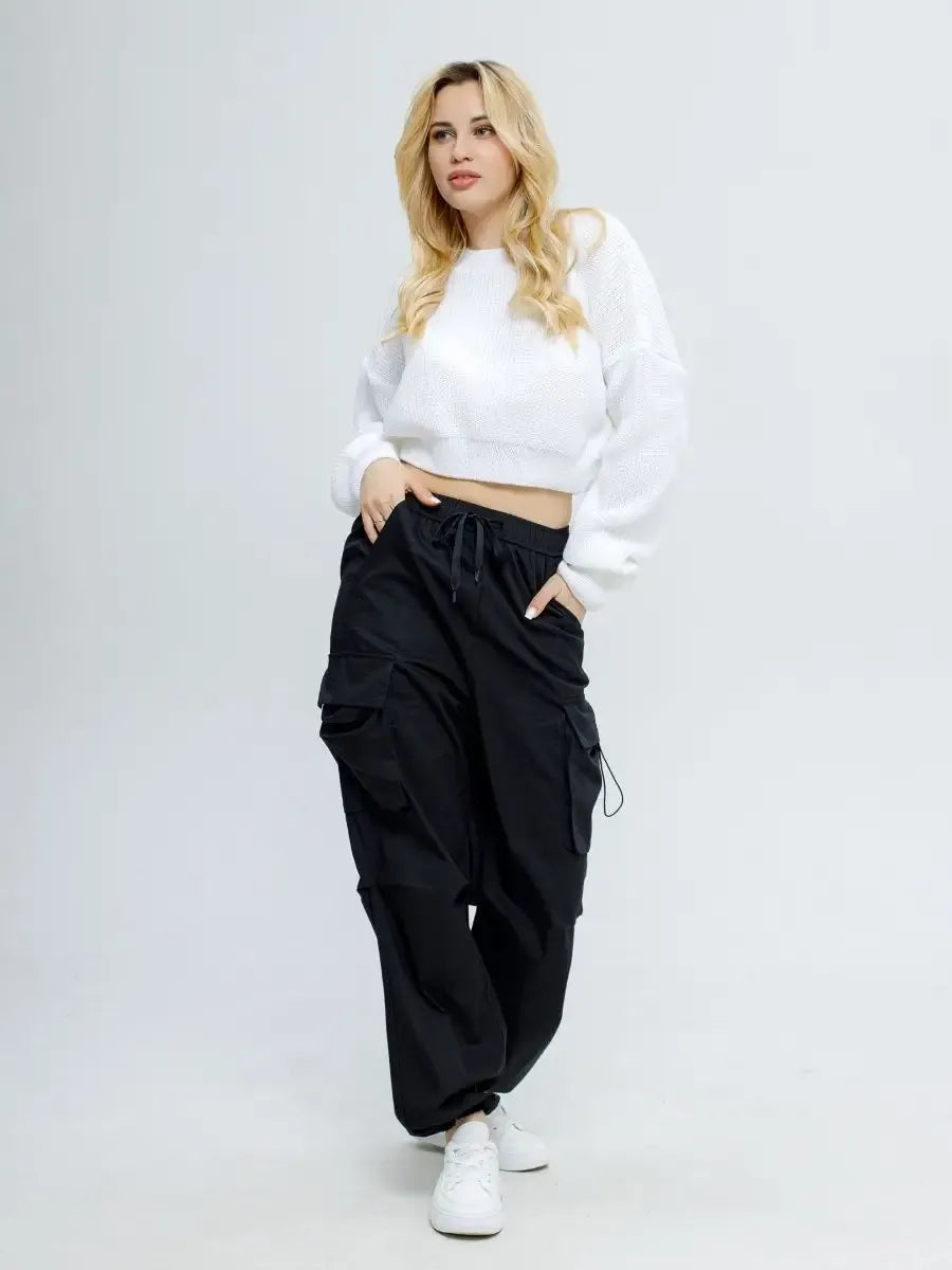Woman modeling the Alba Pullover by Lauven, a lightweight knit in soft white, paired with black cargo pants.