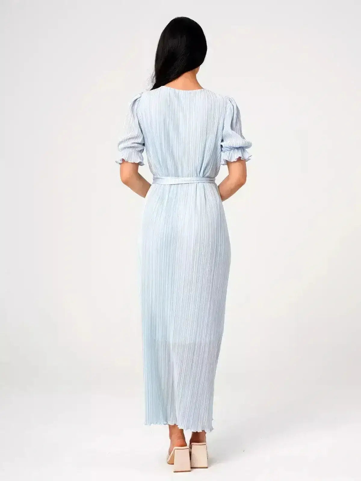 Back view of an elegant woman wearing the Angel Maxi Dress in light blue with pleats and a self-tie waist.