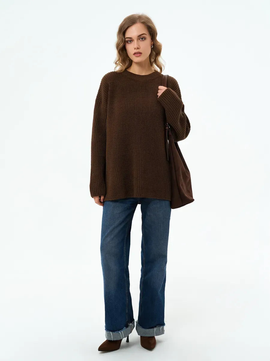 Model wearing the Atlas Sweater by Lauven, an oversized knit in rich brown, paired with jeans and a stylish bag.