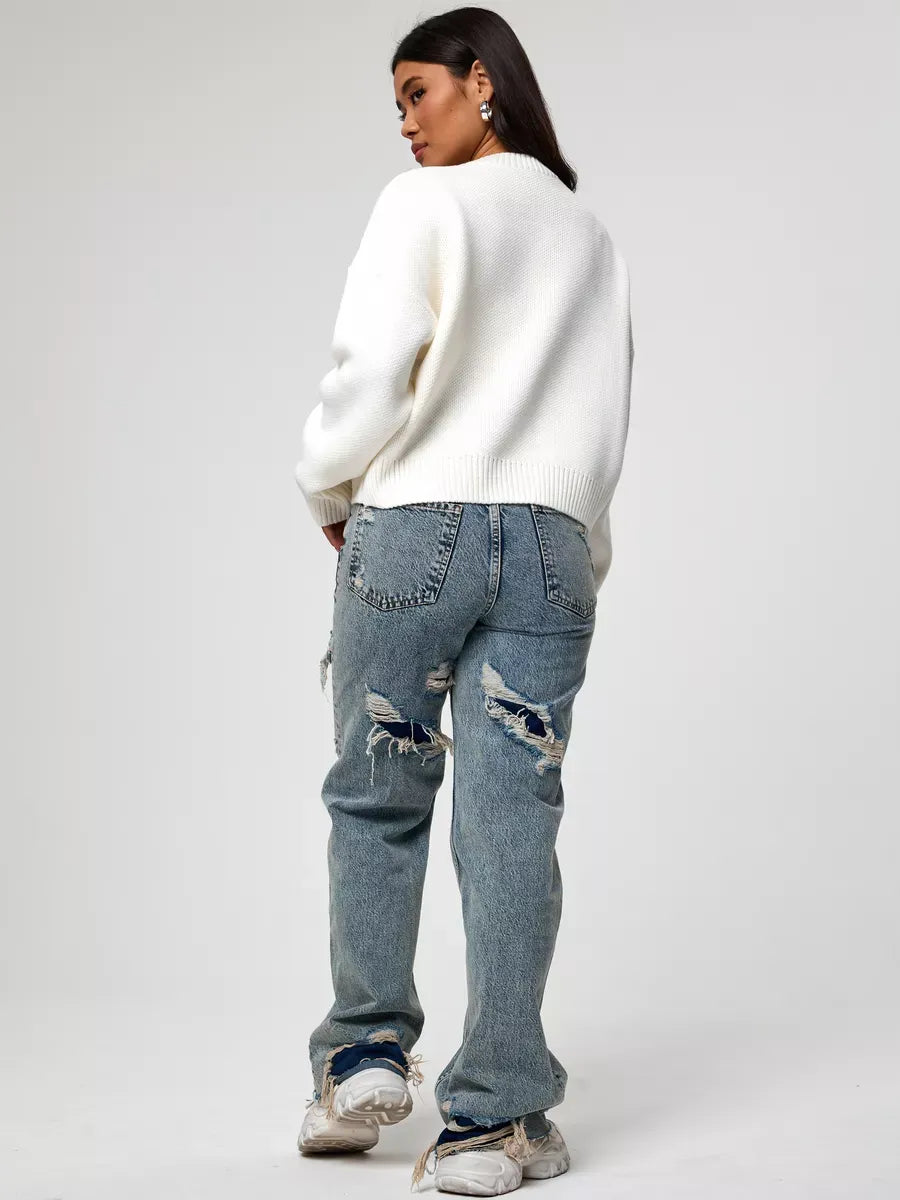 Back view of a woman in a Celeste Pullover, paired with distressed jeans, showcasing modern casual style.