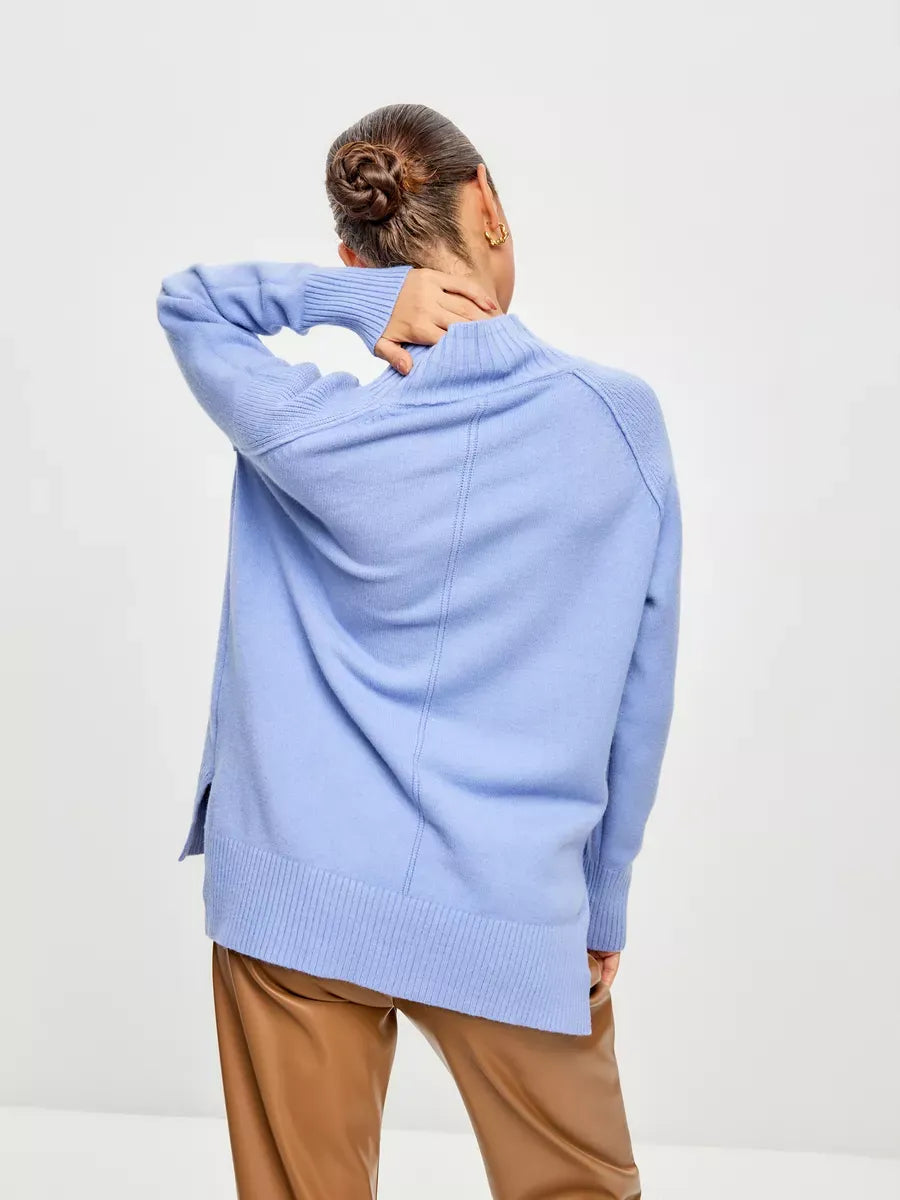 Model wearing Celeste Sweater in soft blue, showcasing the oversized design and high ribbed neckline by Lauven.