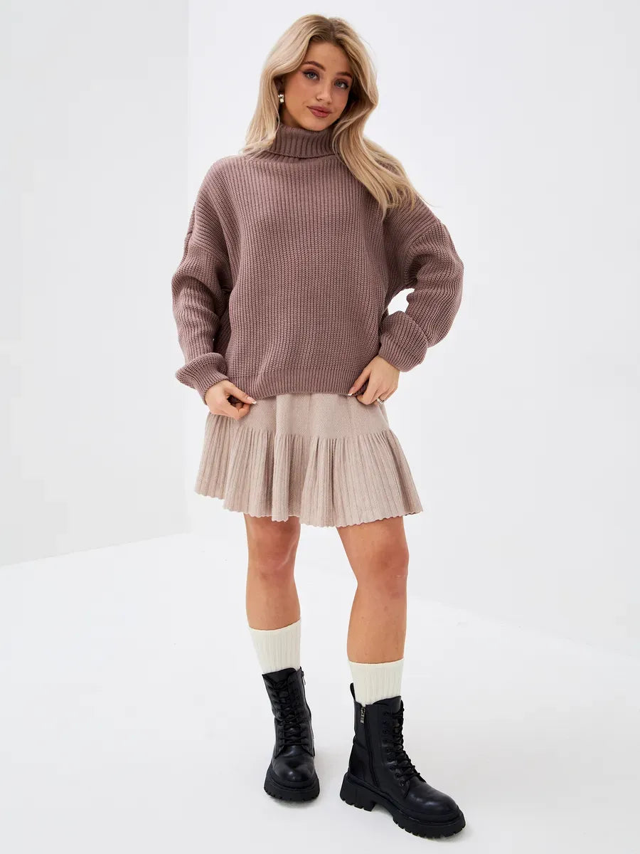 Woman wearing a cozy oversized Florence Sweater by Lauven, styled with a pleated skirt and combat boots.