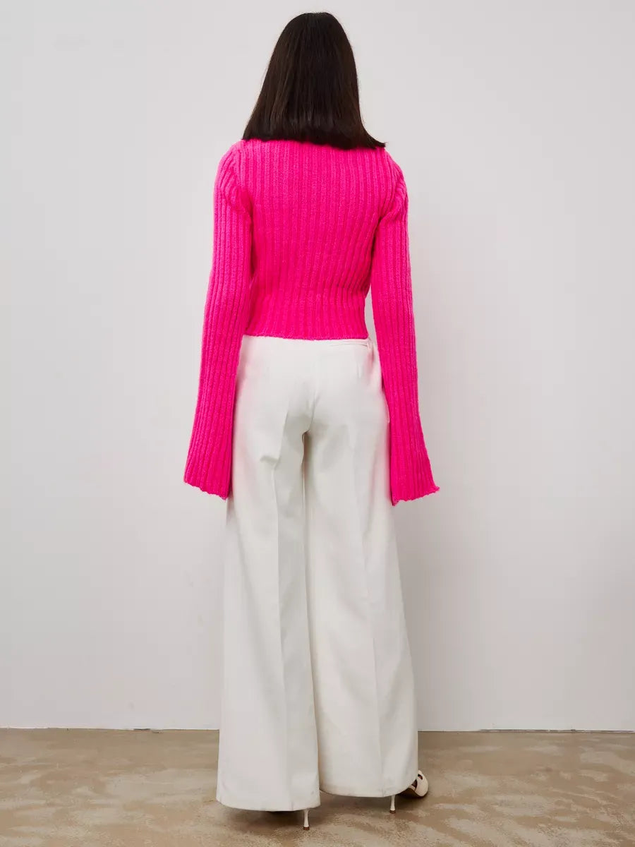 Back view of Selene Sweater by Lauven in bold fuchsia with wide cuffs, styled with white wide-leg pants.