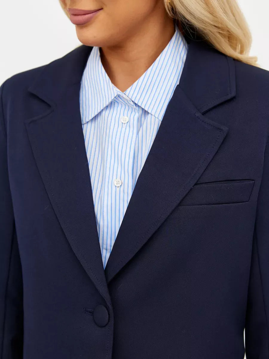 Close-up view of a Navy Blazer by Lauven, featuring classic tailoring and a modern cropped fit, styled with a blue striped shirt.