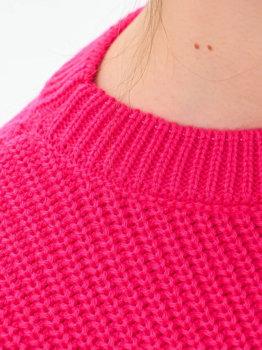 Close-up of the neckline of the Aster Sweater by Lauven in vibrant fuchsia, showcasing its textured knit.