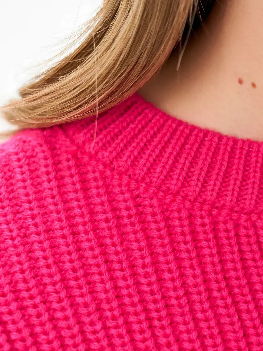 Close-up of the neckline of a Flamingo Sweater by Lauven in bold fuchsia knit, showcasing texture and color.