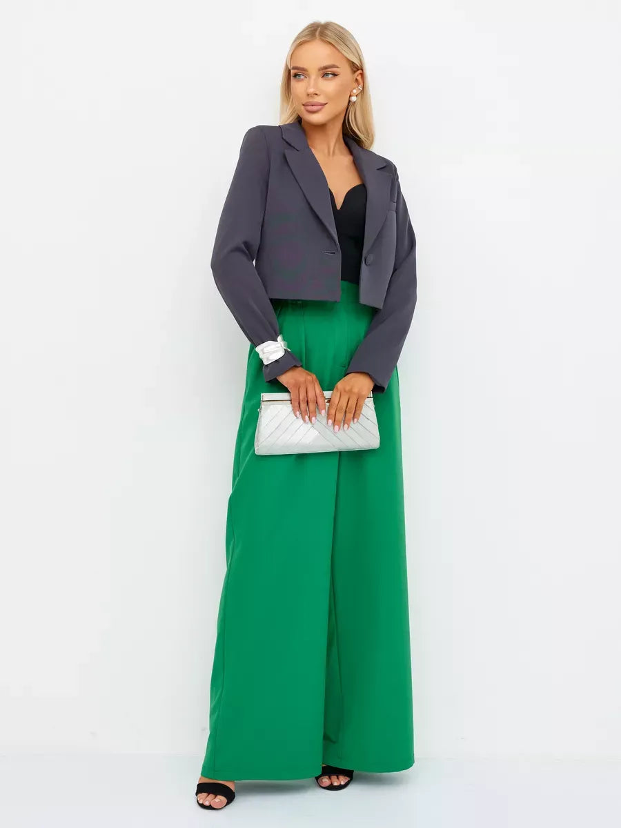 Graphite Blazer by Lauven worn with green pants and a clutch, showcasing a chic cropped silhouette in dark gray.