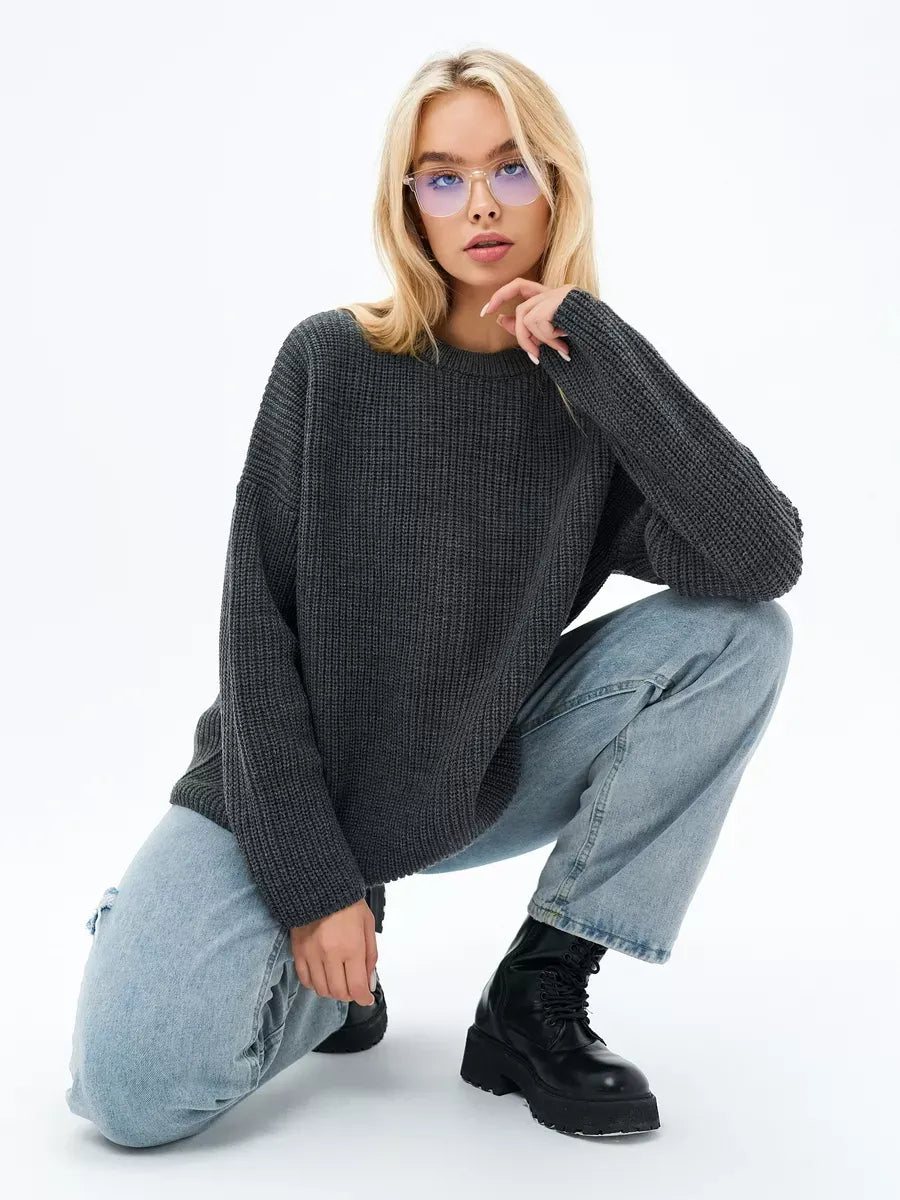 Model showcasing the Luna Sweater by Lauven, an oversized knit sweater in charcoal gray, styled with casual jeans.