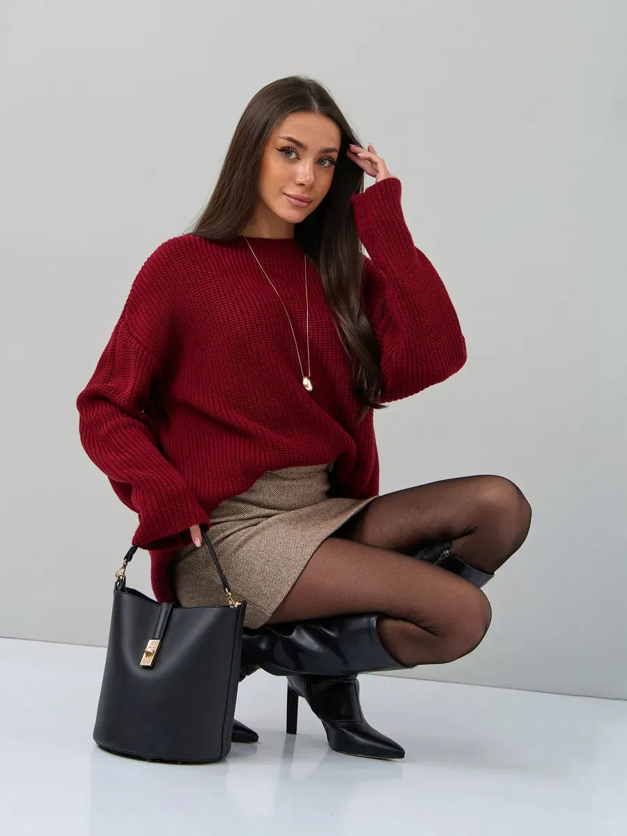 Model wearing the Maribel Sweater by Lauven, an oversized burgundy knit, styled with a skirt and accessories.
