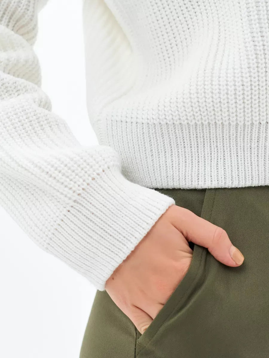 Close-up of a woman's hand in pocket wearing the Nova Sweater by Lauven, showcasing its cozy rib-knit design.