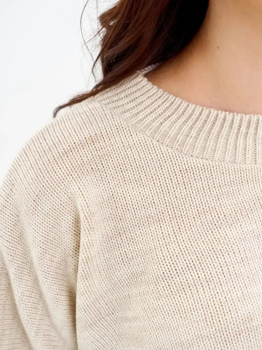 Close-up of Lauven Sand Sweater, a cropped oversized knit in light beige color, showcasing its soft texture.
