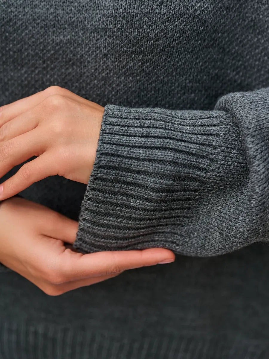Close-up of hands wearing Slate Pullover by Lauven, showcasing the ribbed cuffs and dark gray knit texture.