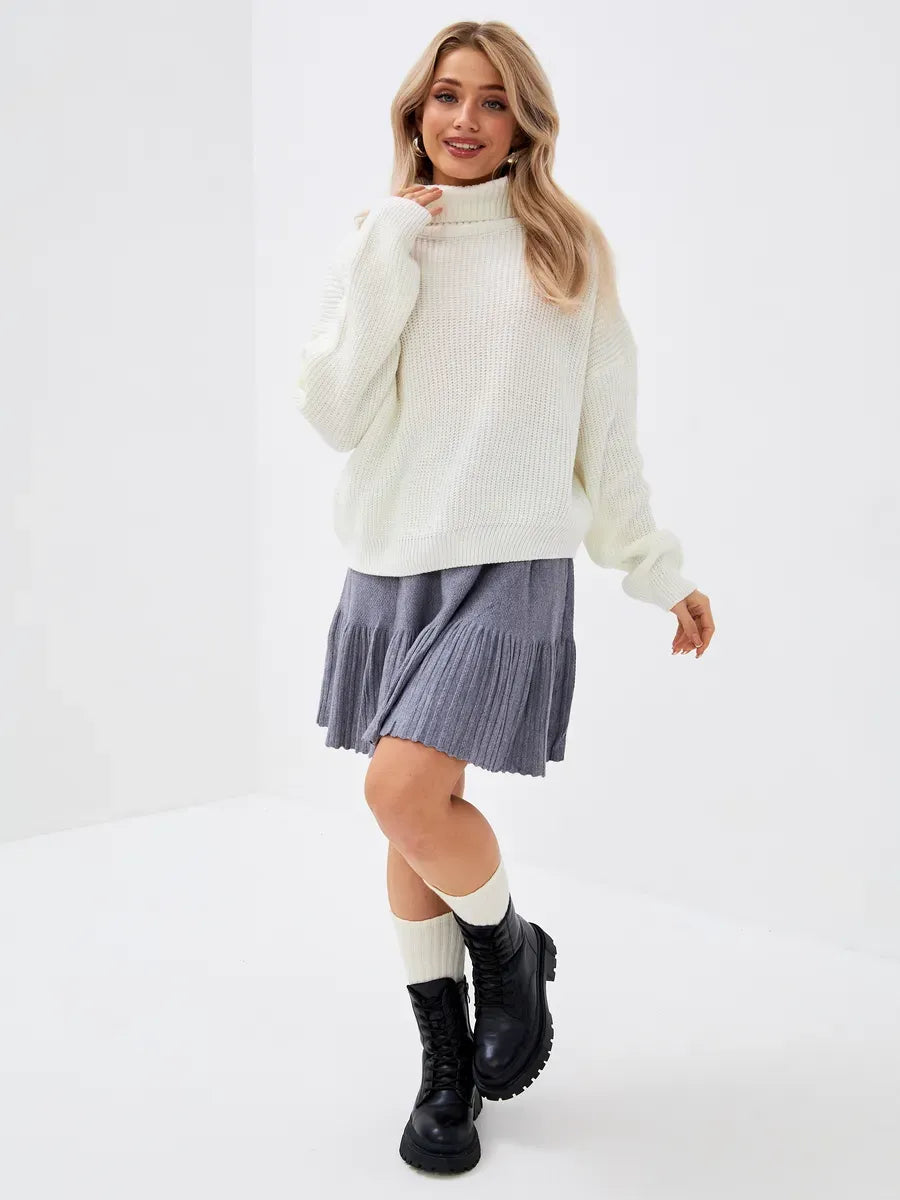 Lyra Sweater by Lauven, an oversized knit high neck in ivory paired with a pleated skirt and combat boots.