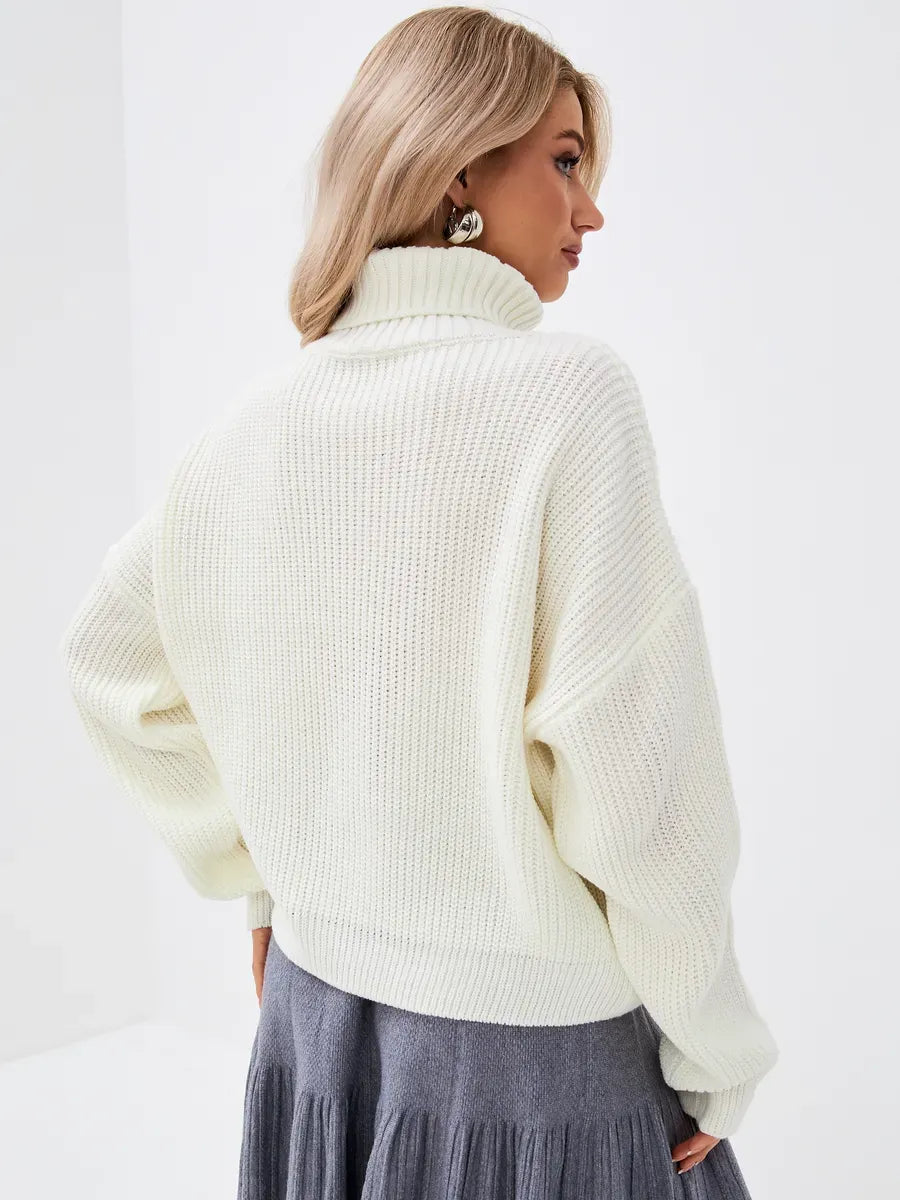Rear view of a model wearing the Luaven Lyra Sweater, an oversized ivory knit with a high neck.