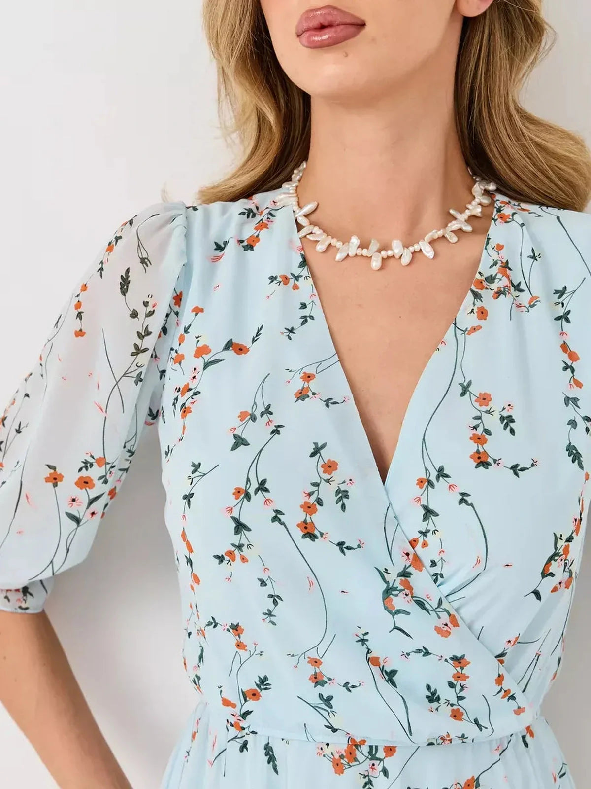 Model wearing Mara Mini Dress by Lauven, featuring a light blue floral pattern and V-neckline.