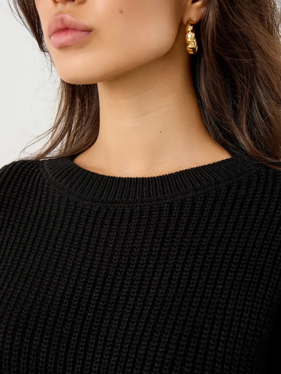 Close-up of a woman's neckline in the Nola Sweater by Lauven, showcasing its black chunky ribbed knit texture.