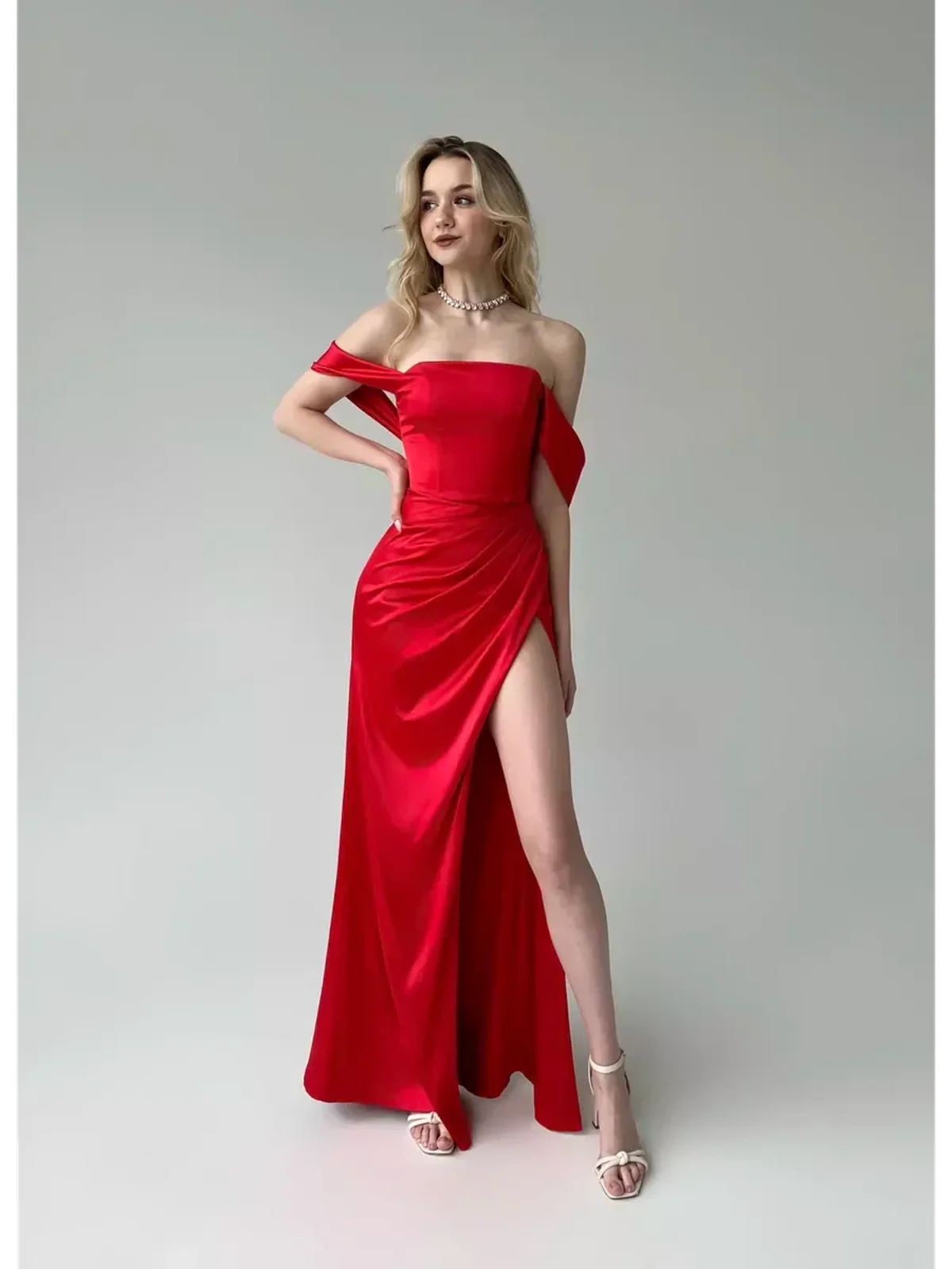 Model wearing a stunning Lauven Vega Party Dress, a red satin off-shoulder gown featuring elegant draping and a high slit.
