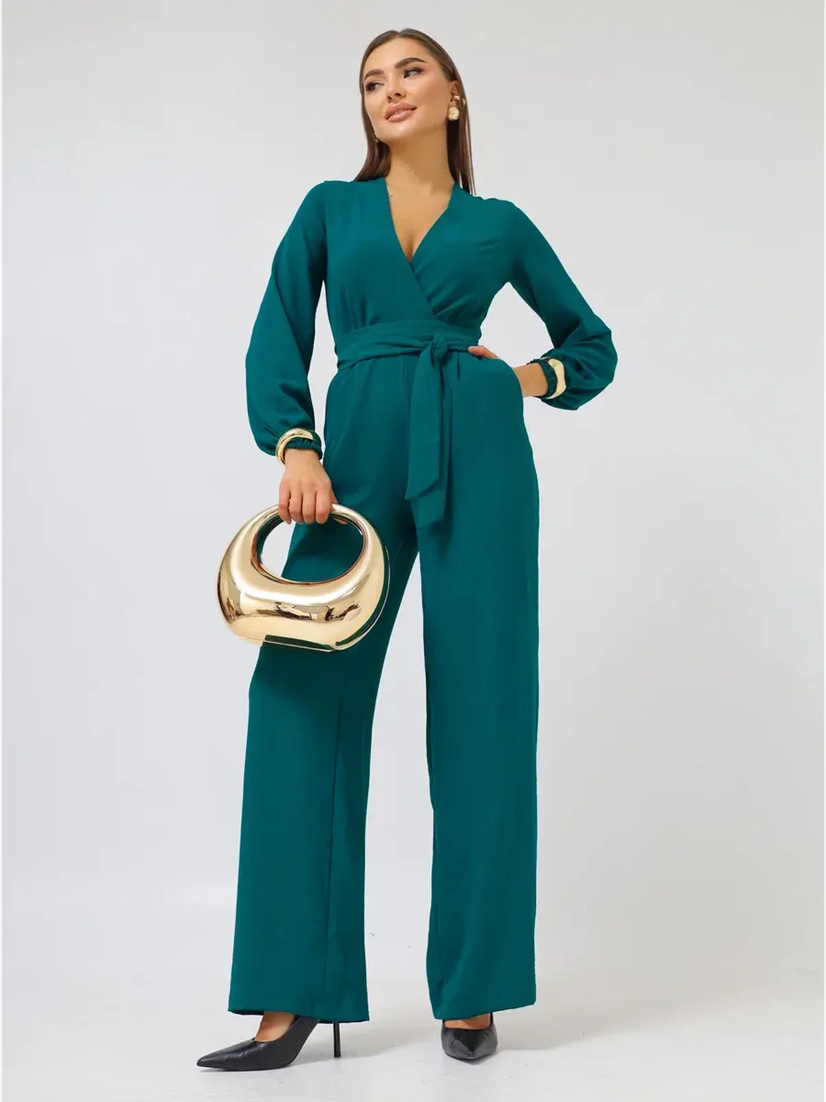 Zoe Jumpsuit by Lauven featuring wide-leg design, deep V-neckline, and self-tie belt, styled with a gold handbag.