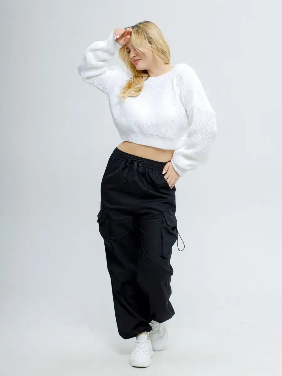 Model showcasing the Alba Pullover by Lauven, a lightweight knit in soft white, styled with black cargo pants.