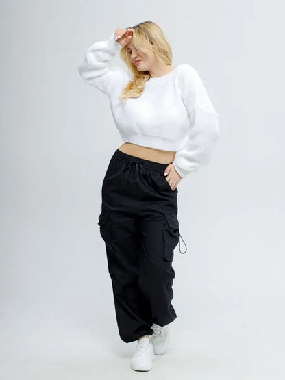 Model showcasing the Alba Pullover by Lauven, a lightweight knit in soft white, styled with black cargo pants.
