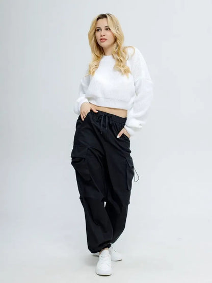 Woman modeling the Alba Pullover by Lauven, a lightweight knit in soft white, paired with black cargo pants.