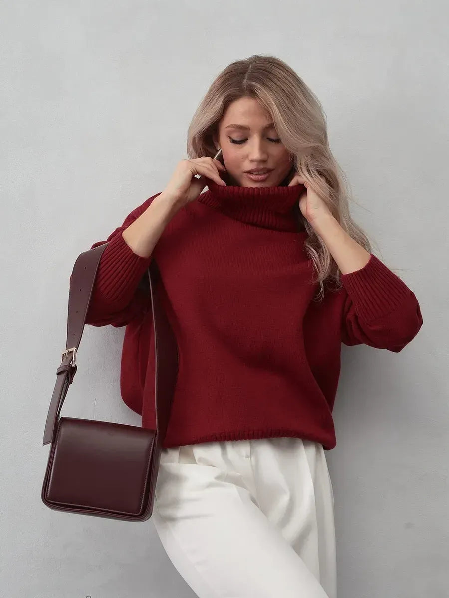 Model wearing Arden Sweater in burgundy with modern elegance and a stylish handbag.