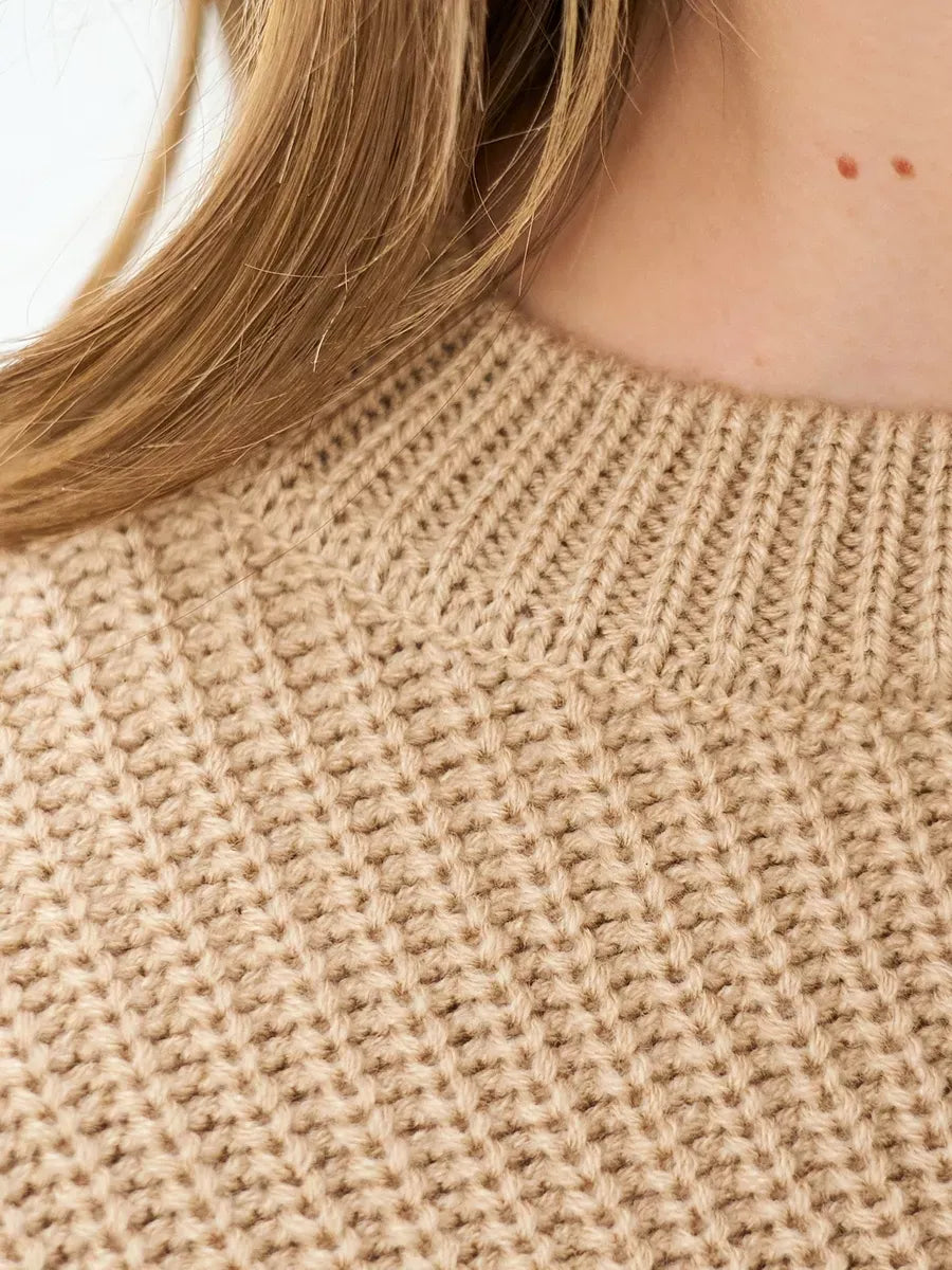 Close-up of the textured fabric of the Lauven Cappuccino Sweater in warm beige, showcasing its cozy knit design.