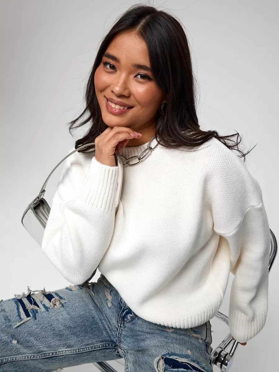 Woman smiling in a soft ivory Celeste Pullover, an oversized cropped women's sweater by Lauven.