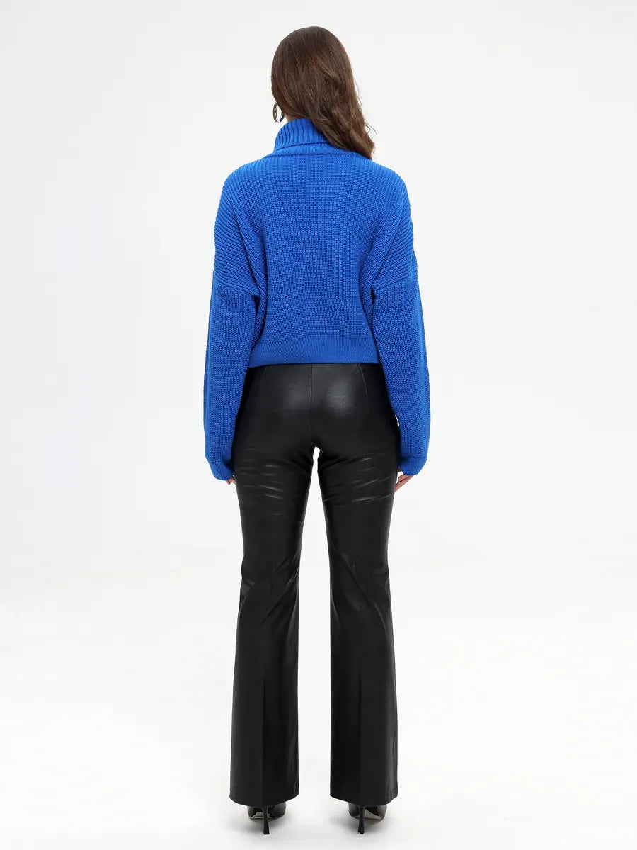 Celeste Sweater by Lauven - Oversized knit turtleneck in vibrant blue worn with black flared pants from the back.