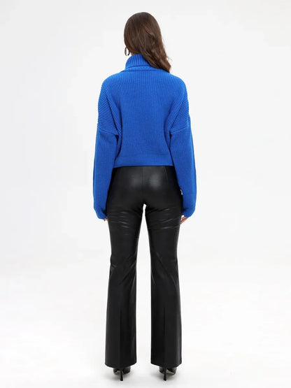Celeste Sweater by Lauven - Oversized knit turtleneck in vibrant blue worn with black flared pants from the back.