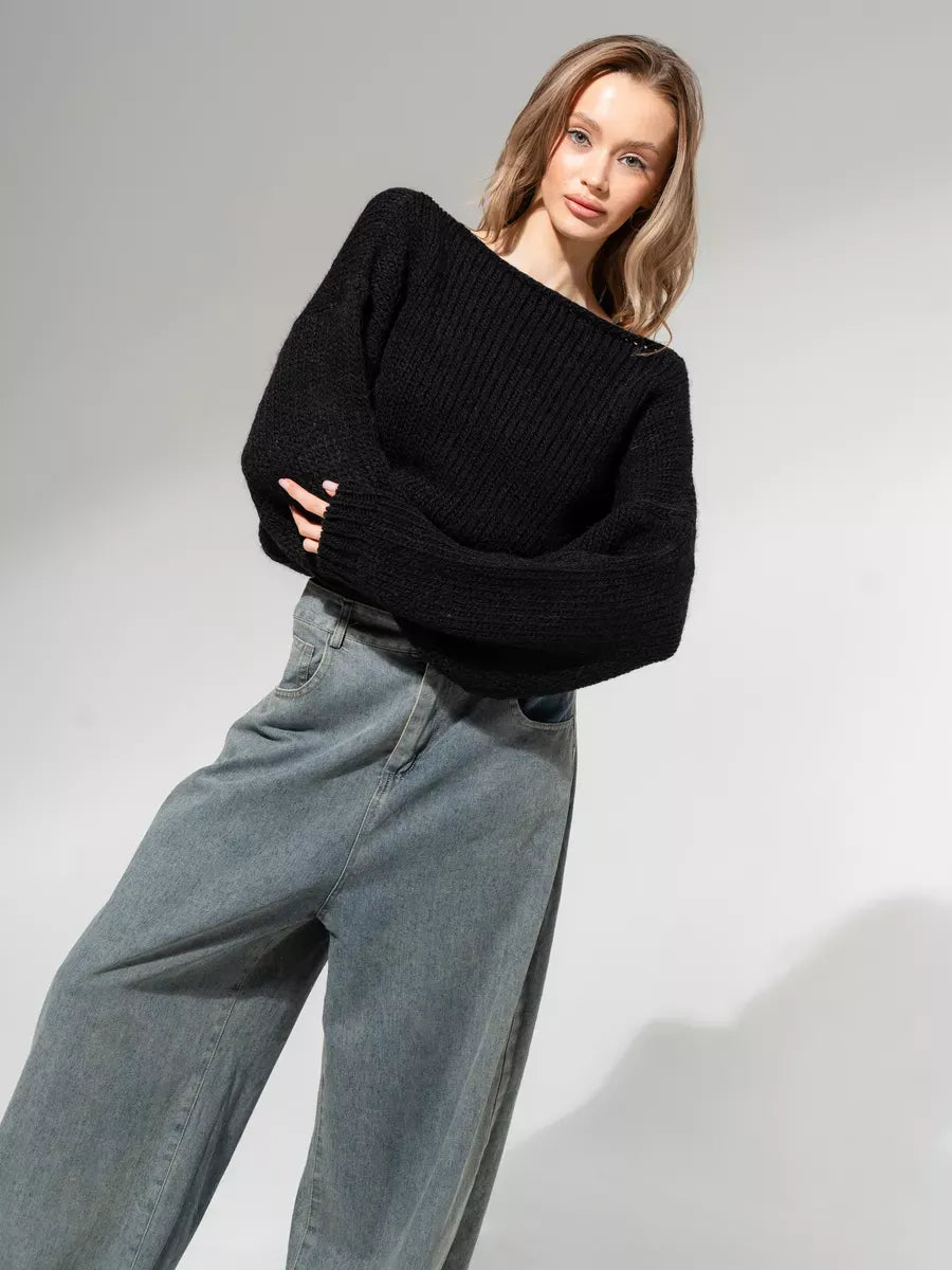 Woman wearing Noir Sweater by Lauven, an oversized off-shoulder knit in classic black, paired with relaxed jeans.