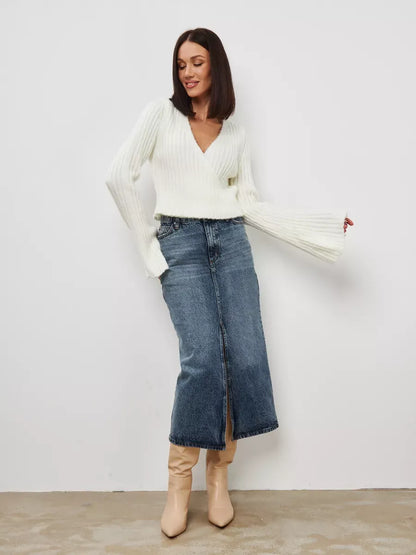 Model wearing the Lyra Sweater by Lauven, a cropped cream knit with a V-neck and wide sleeves, paired with a denim skirt.