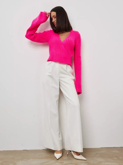 Selene Sweater by Lauven in fuchsia, cropped V-neck knit with wide cuffs, styled with white trousers.