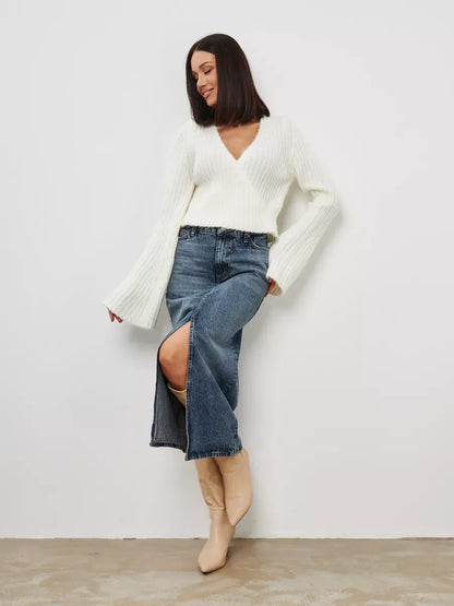 Model wearing Lyra Sweater by Lauven, a cropped cream knit with V-neck and wide sleeves, styled with denim skirt.