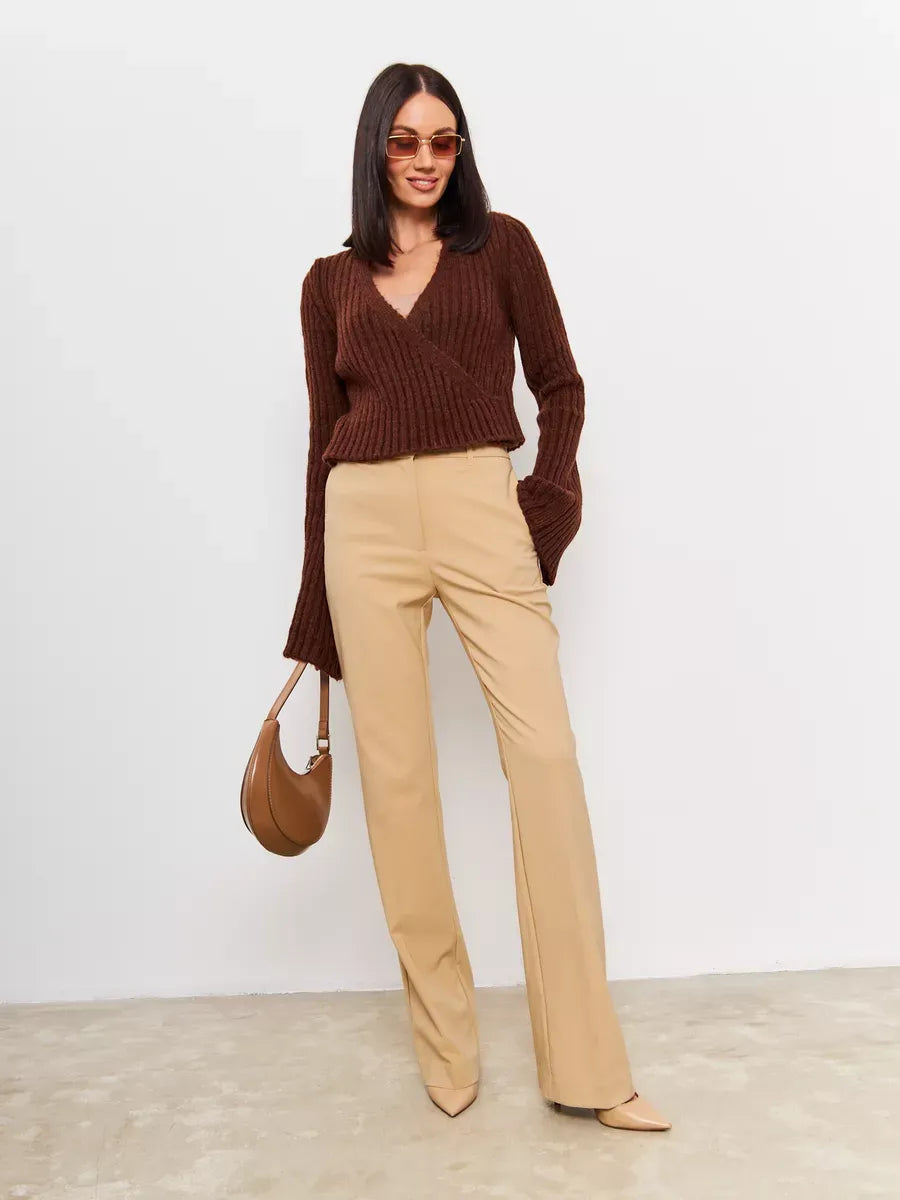 Model wearing an Orion Sweater by Lauven, featuring a brown cropped knit and wide sleeves, paired with chic beige trousers.