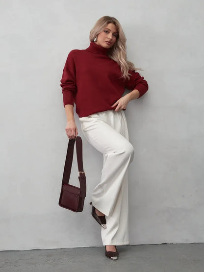 Arden Sweater by Lauven in burgundy worn with white pants and a matching bag, showcasing modern elegance.