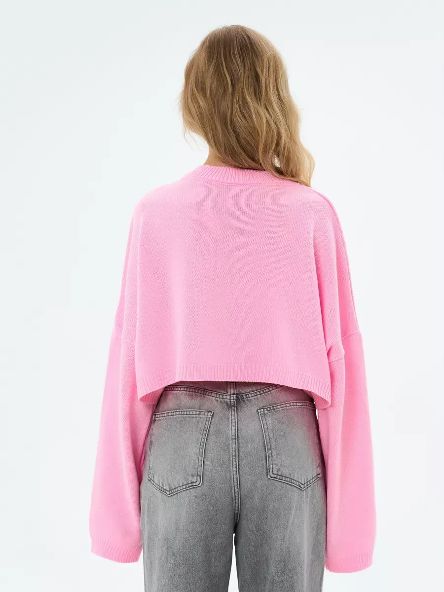Back view of the Lauven Candy Sweater, a cropped oversized knit in soft pink, paired with gray jeans.