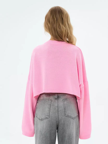 Back view of the Lauven Candy Sweater, a cropped oversized knit in soft pink, paired with gray jeans.