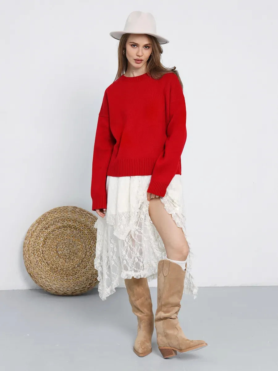 Woman wearing Ember Pullover by Lauven, a bold red oversized cropped sweater, styled with a lace skirt and boots.
