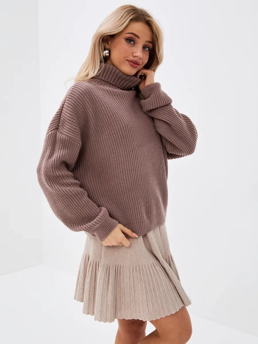Florence Sweater by Lauven in oversized knit with turtleneck, styled with a pleated skirt, perfect for transitional weather.