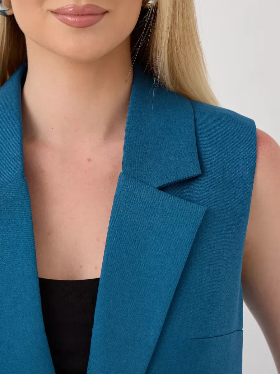Close-up of a woman wearing a sleeveless teal vest from the Marine Suit Set by Lauven.