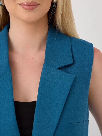 Close-up of a woman wearing a sleeveless teal vest from the Marine Suit Set by Lauven.
