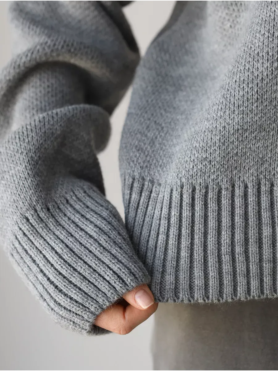 Close-up of the sleeve and hem of the Nova Pullover by Lauven, showcasing its soft silver-gray fabric and ribbed design.