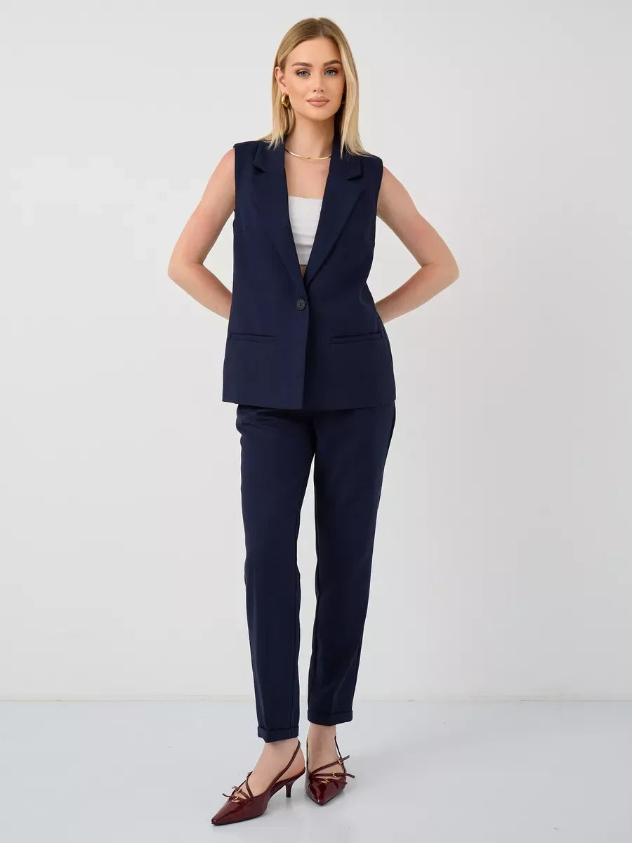 Model wearing the Orion Suit Set by Lauven, featuring a sleeveless navy vest and high-waist pants.
