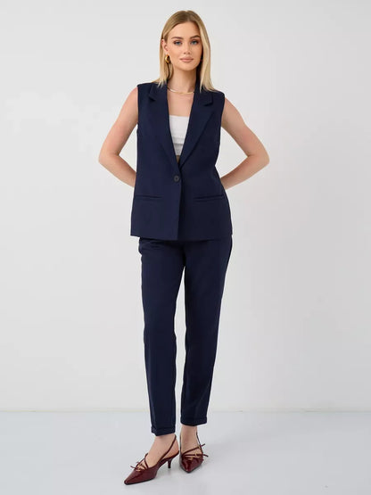 Model wearing the Orion Suit Set by Lauven, featuring a sleeveless navy vest and high-waist pants.