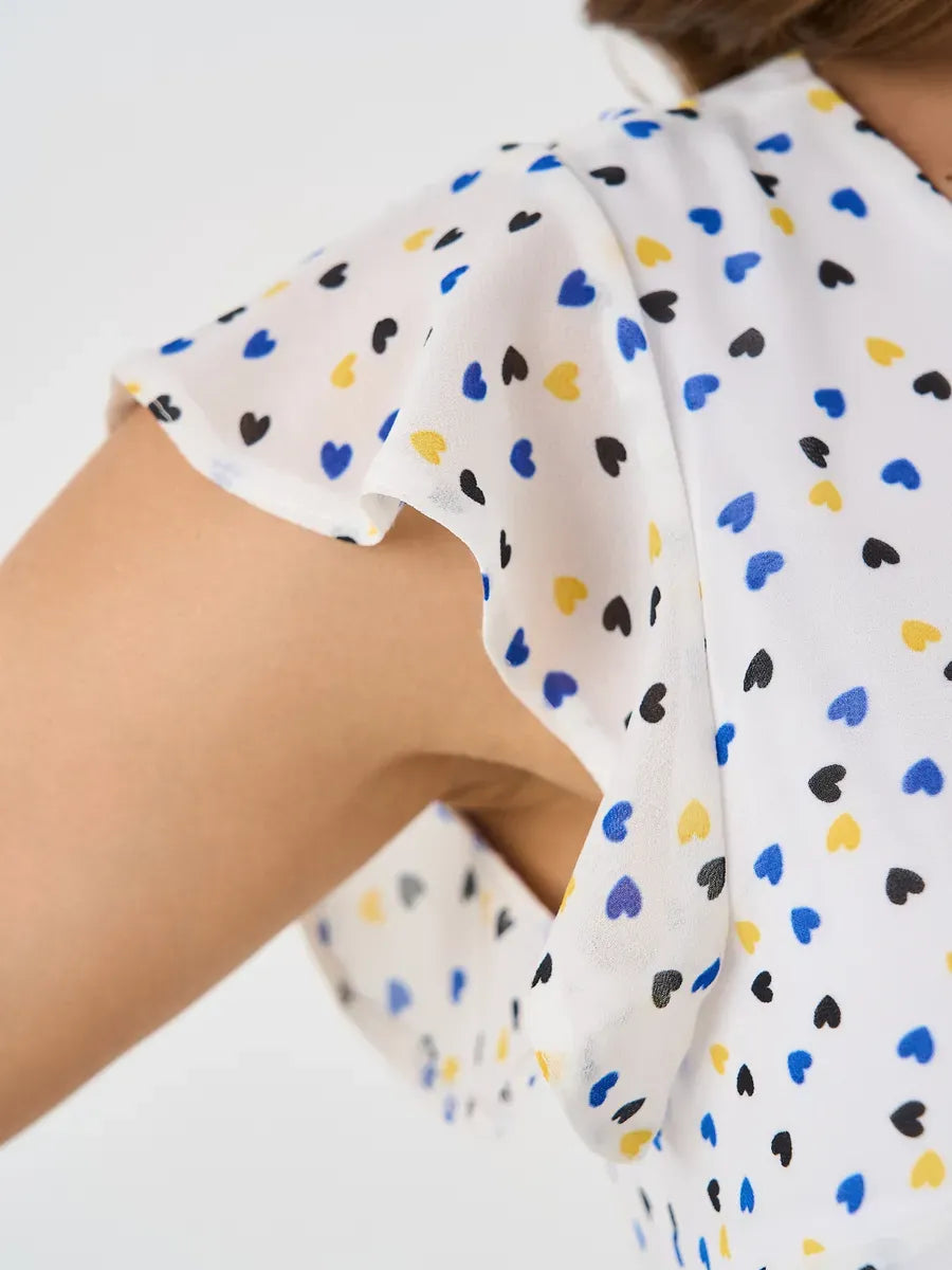 Close-up of ruffle sleeve on Pearl Mini Dress by Lauven, featuring a playful heart pattern in blue, black, and yellow.