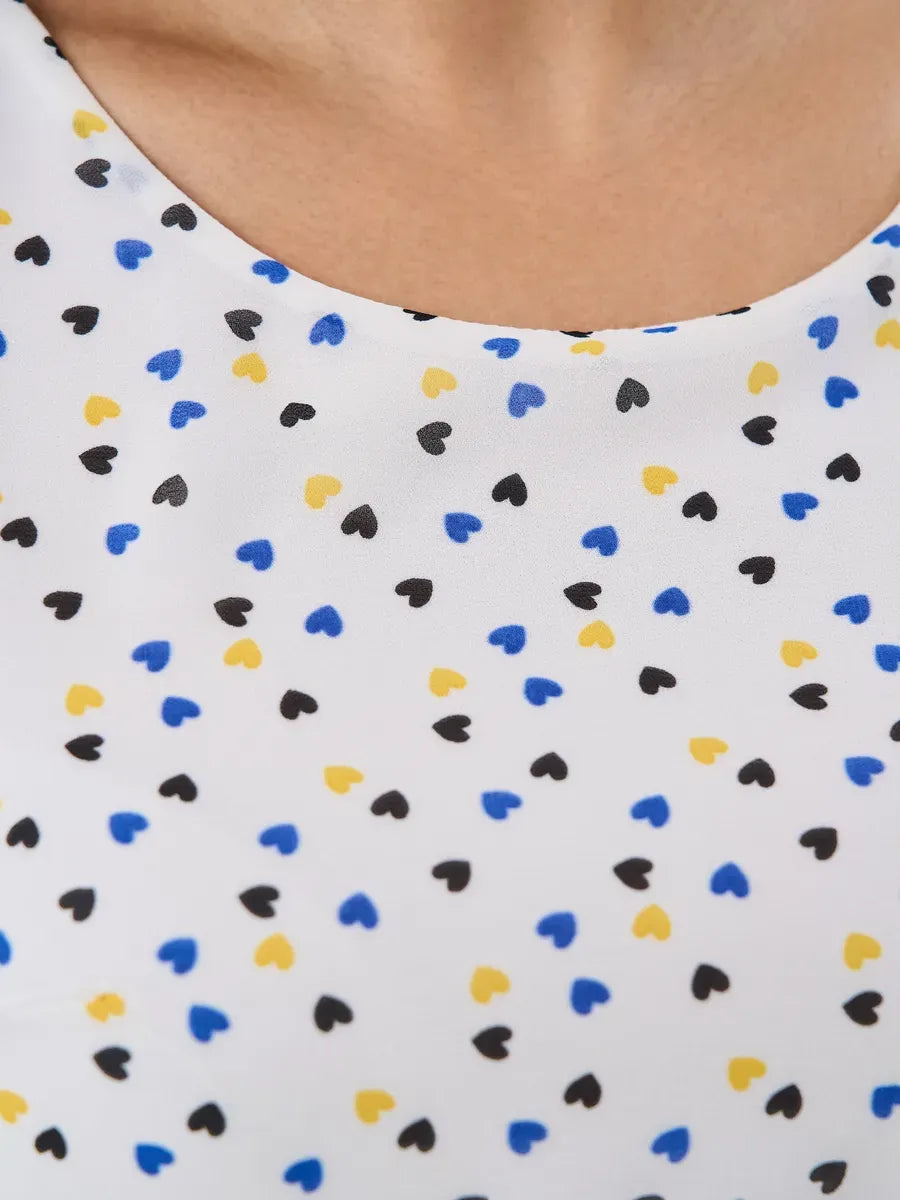 Close-up of Pearl Mini Dress by Lauven featuring a white fabric adorned with colorful heart patterns.