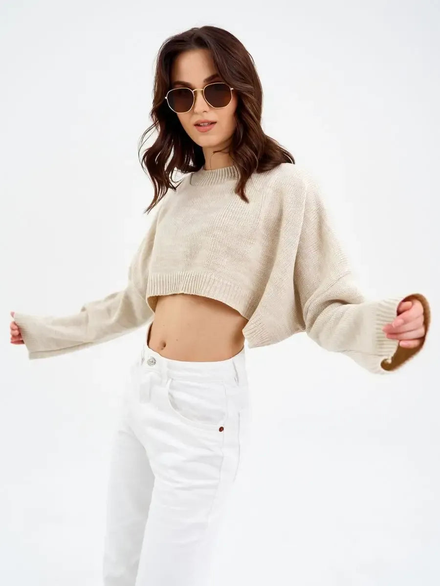 Model wearing Sand Sweater by Lauven, a cropped oversized knit in light beige, styled with white jeans.