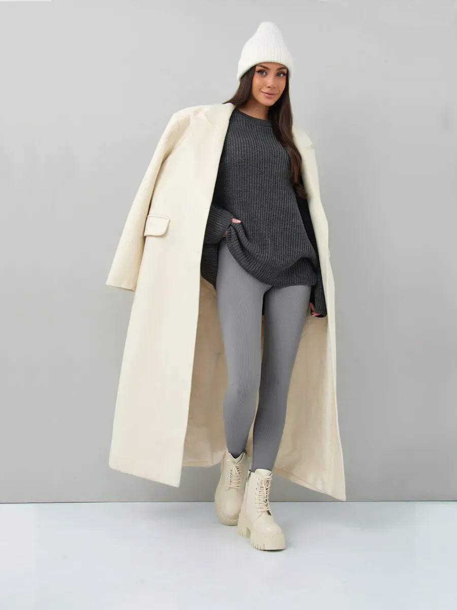 Model wearing Vera Sweater by Lauven, oversized dark gray knit with gray leggings and cream coat.